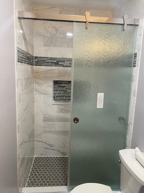 A bathroom with a sliding glass shower door and a toilet.