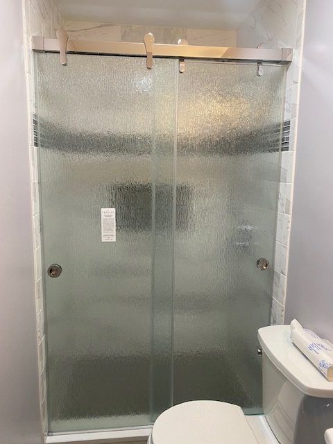 A bathroom with a sliding glass shower door and a toilet.