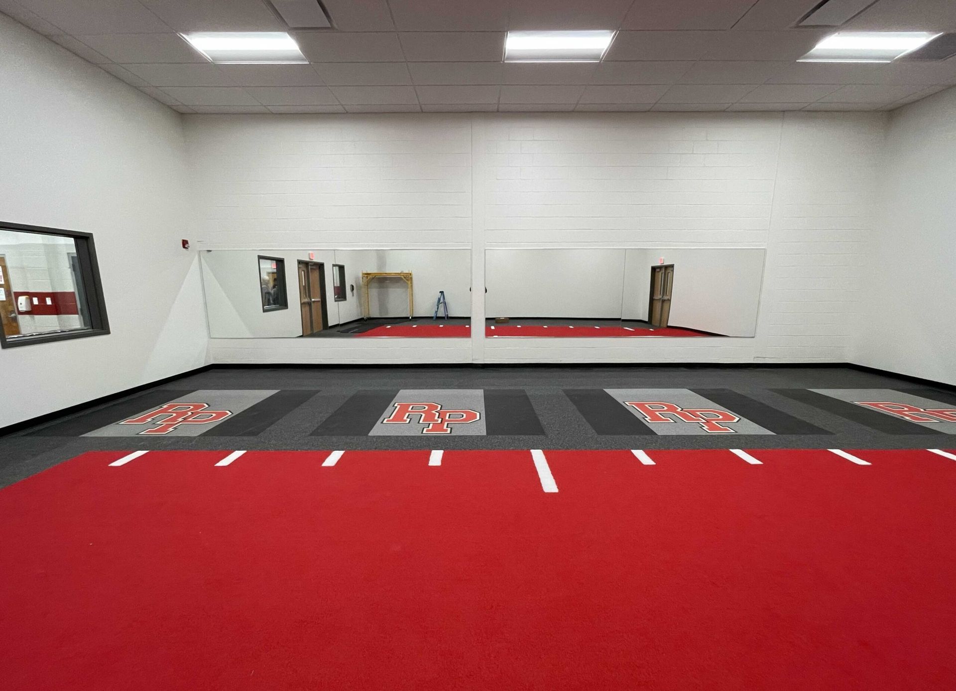 A large empty room with a red carpet and mirrors.