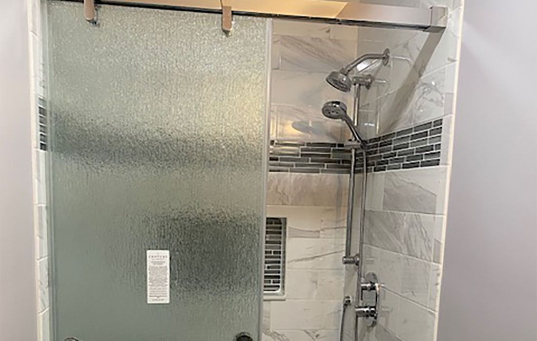 A shower with a sliding glass door and a shower head.