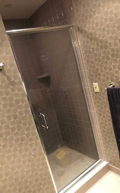 A bathroom with a walk in shower with a glass door.