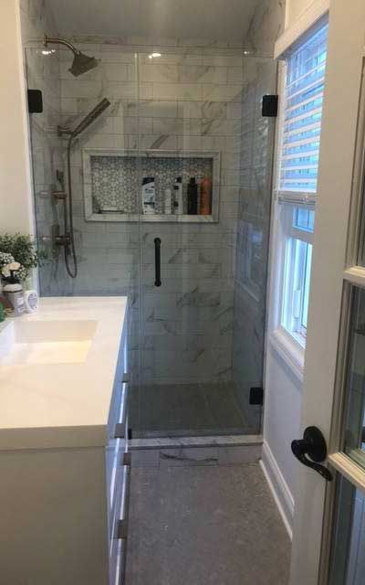 A bathroom with a walk in shower , sink , and window.