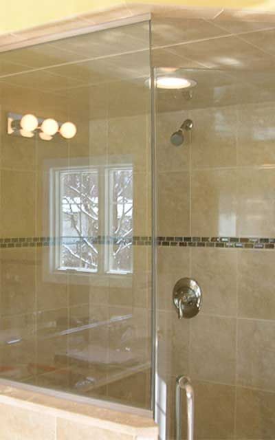 A bathroom with a glass shower door and a window.
