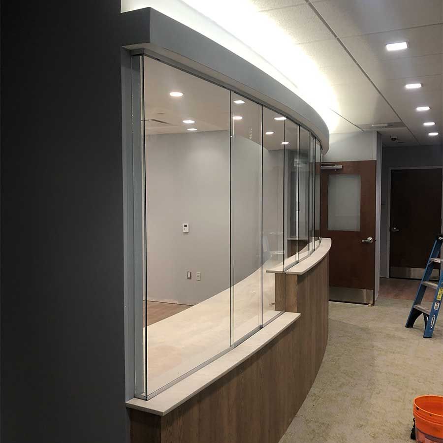 A long hallway with a curved glass wall and a ladder.