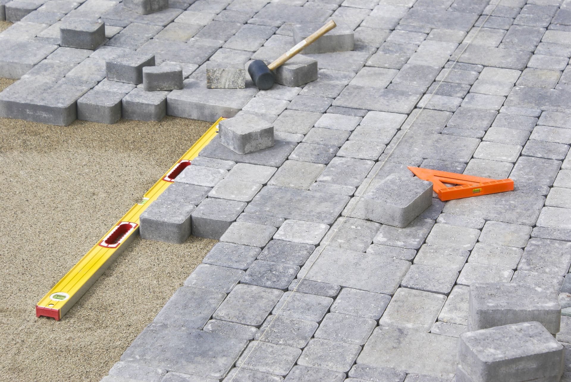 Construction tools and paving blocks on a stone patio under repair