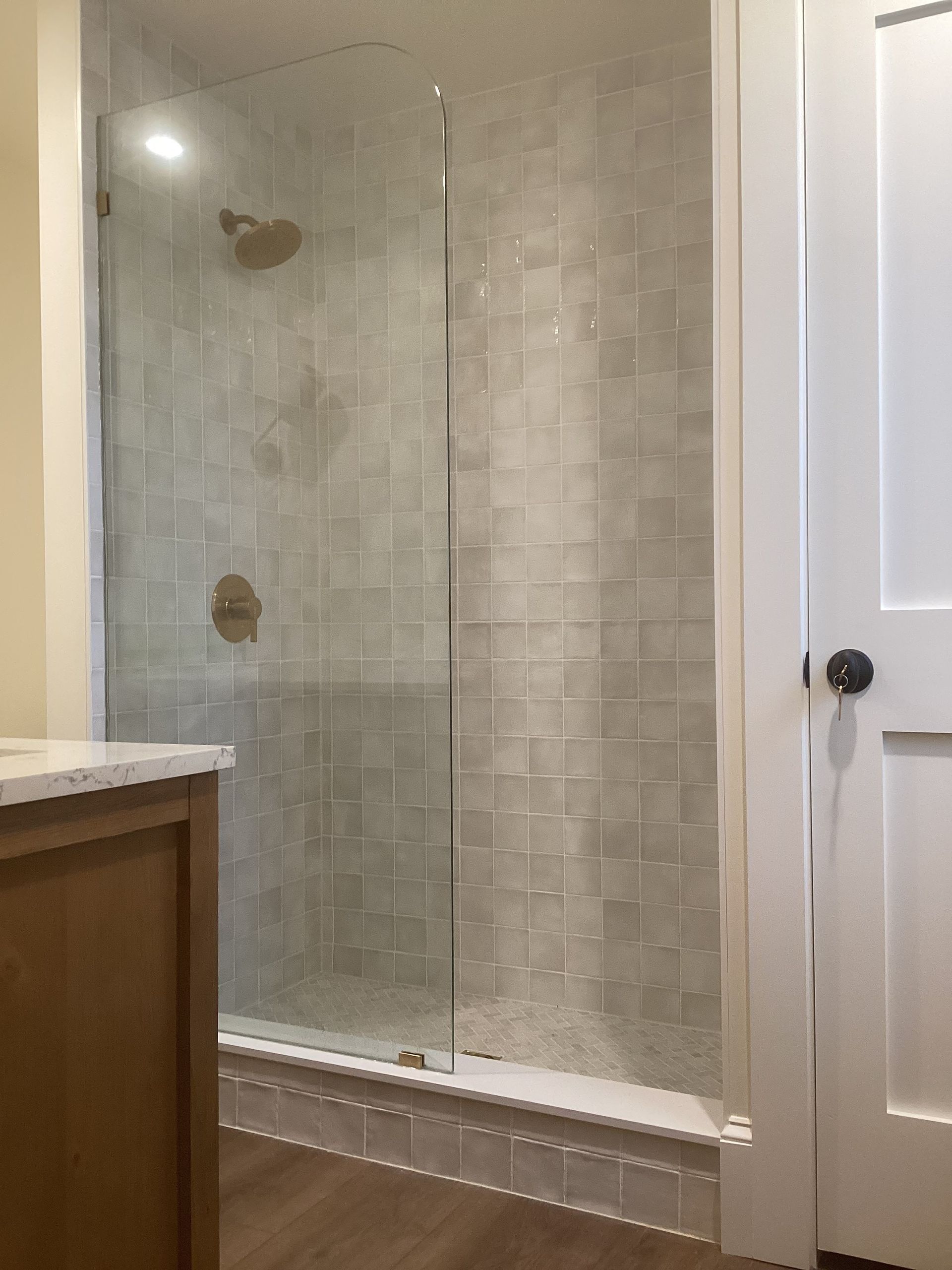 A bathroom with a walk in shower with a glass door.