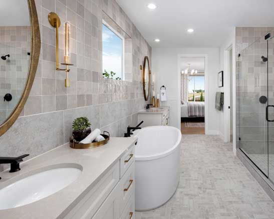 A bathroom with a tub , sink , mirror and shower.