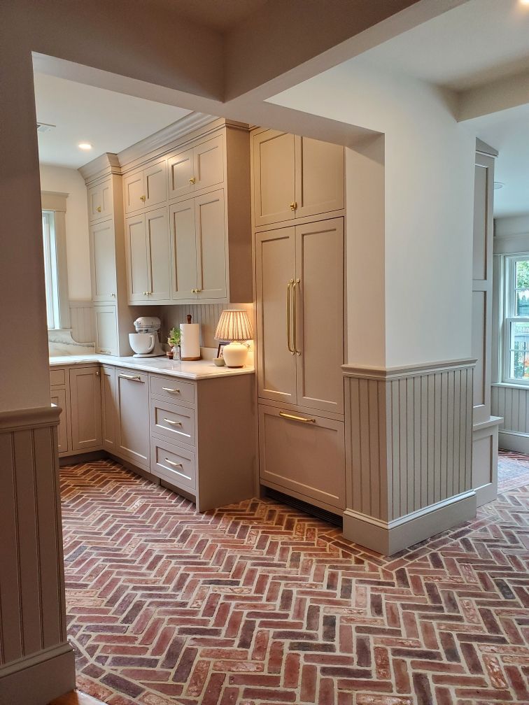Kitchen with gray cabinets, brick herringbone floor, and a built-in refrigerator.