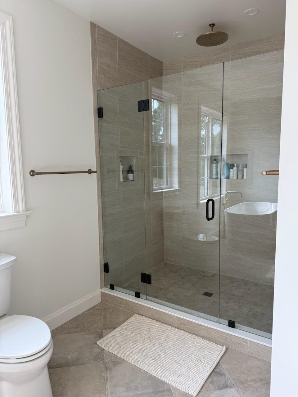 A bathroom with a toilet, sink and shower with a glass door.
