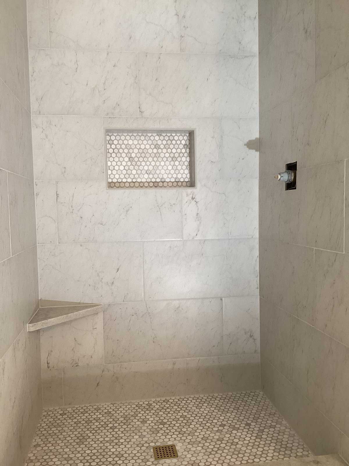 A bathroom with a walk in shower and a bench.