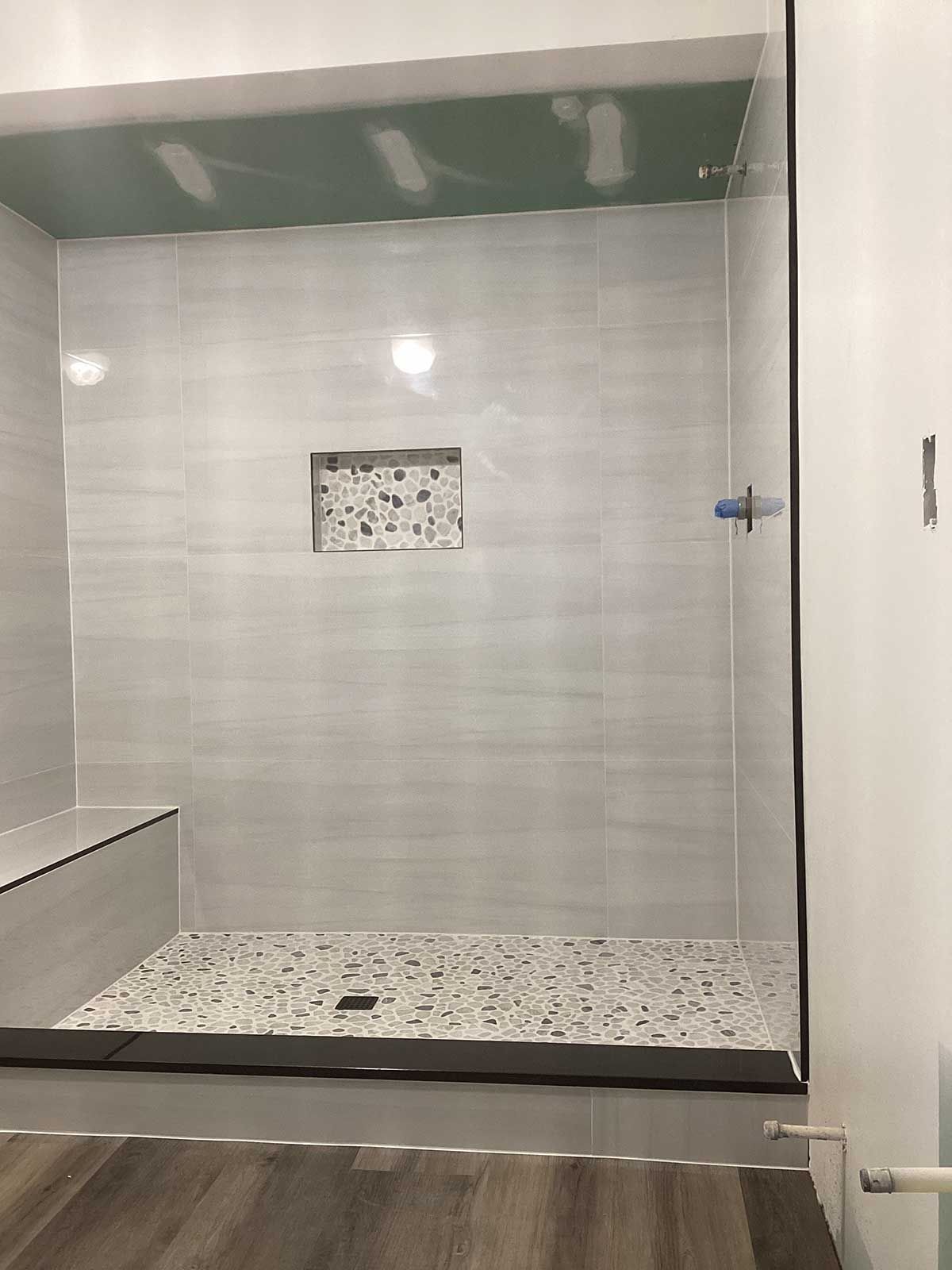 A bathroom with a walk in shower and a bench.