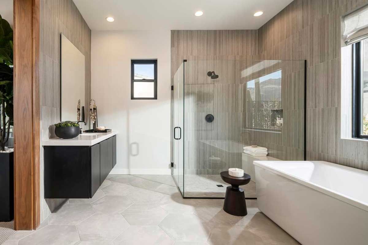 A bathroom with a tub , sink , shower and mirror.