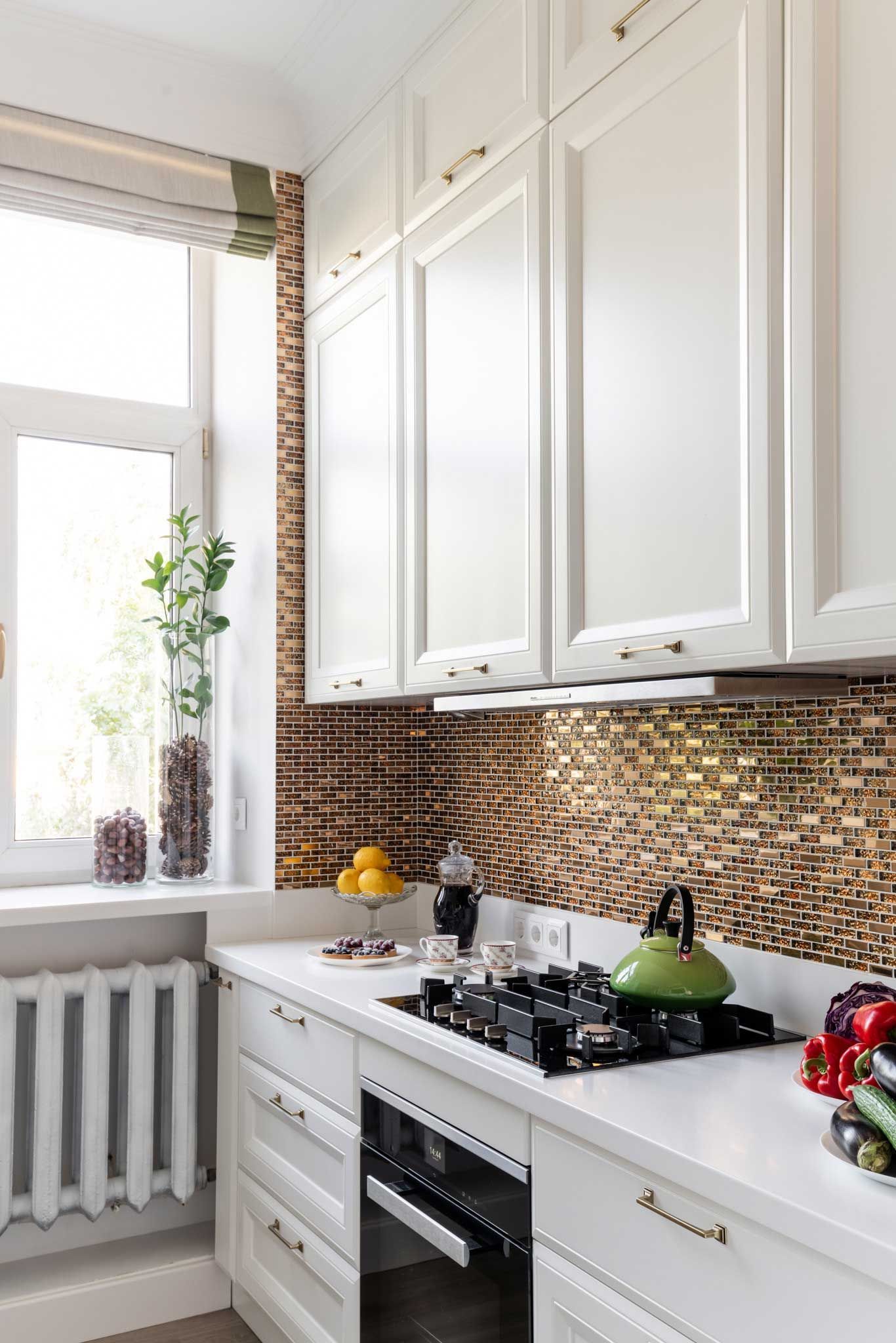 A kitchen with white cabinets and a stove top oven.