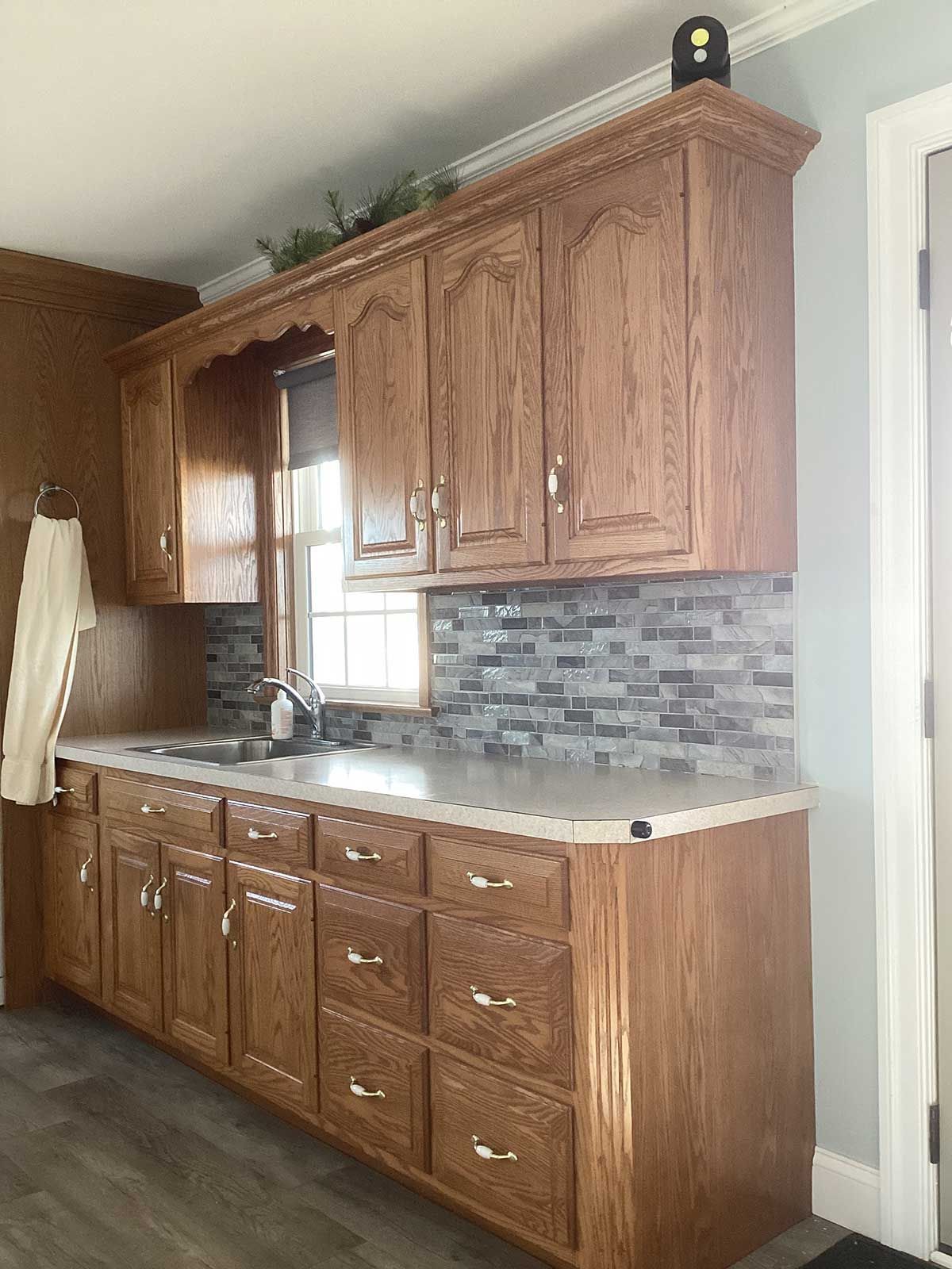 A kitchen with wooden cabinets , drawers , a sink and a window.