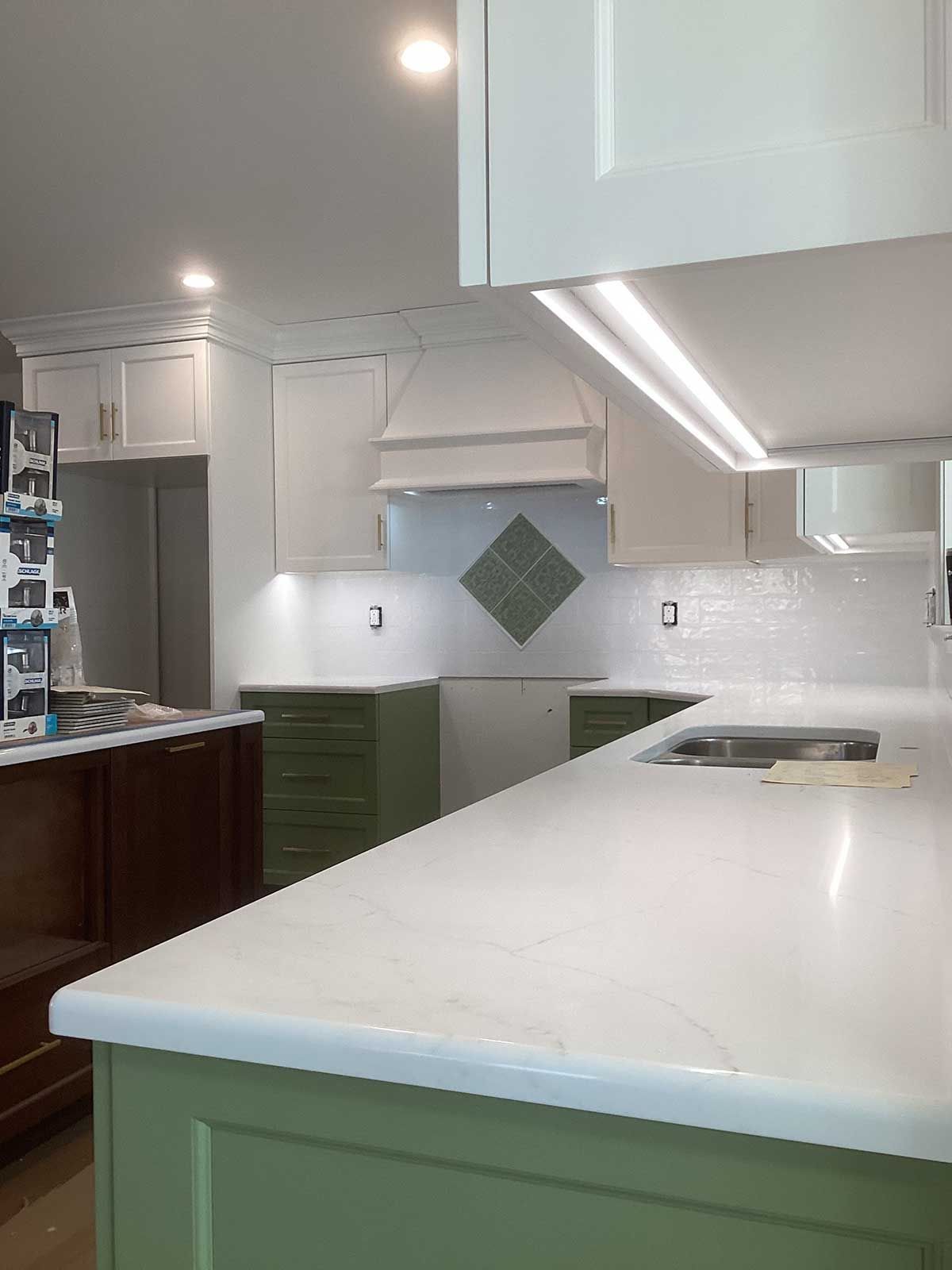 A kitchen with green cabinets and white counter tops