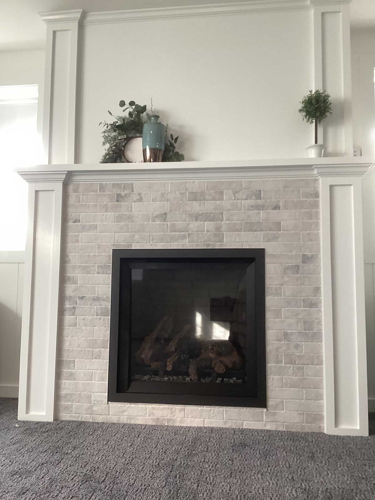 A living room with a fireplace and a gray carpet.