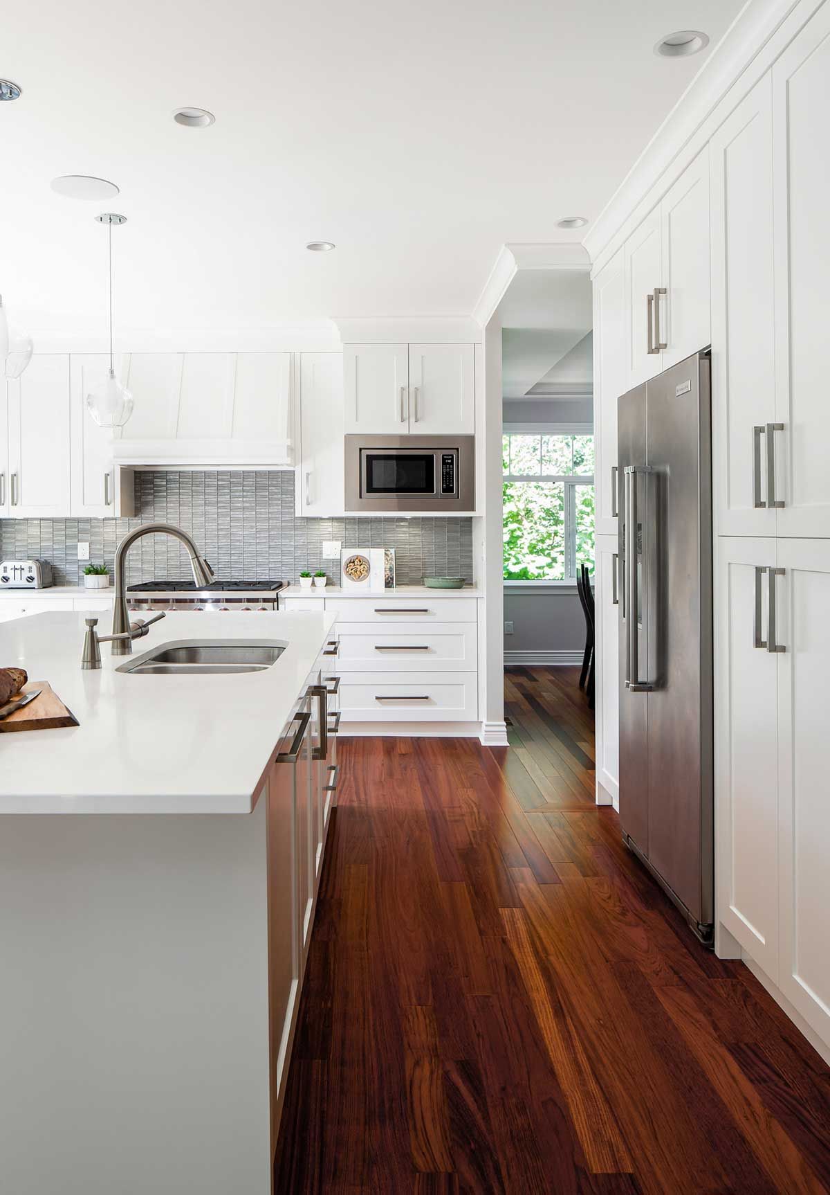 A kitchen with white cabinets , stainless steel appliances , and hardwood floors.