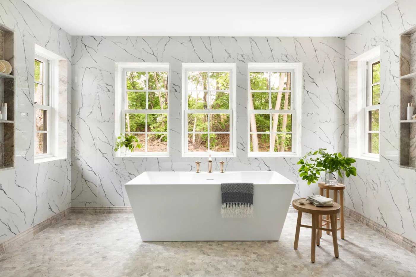 A bathroom with a bathtub and three windows.