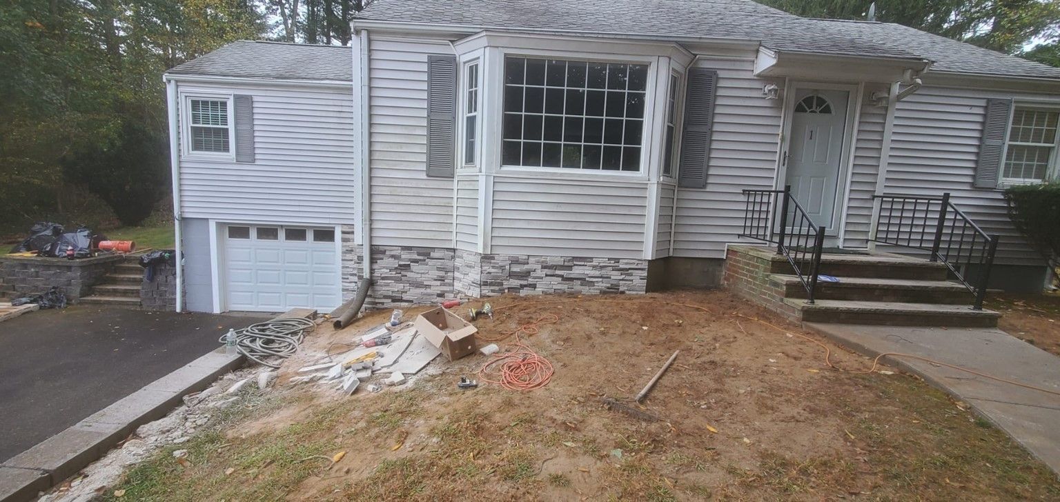 A white house with a garage and stairs in front of it.