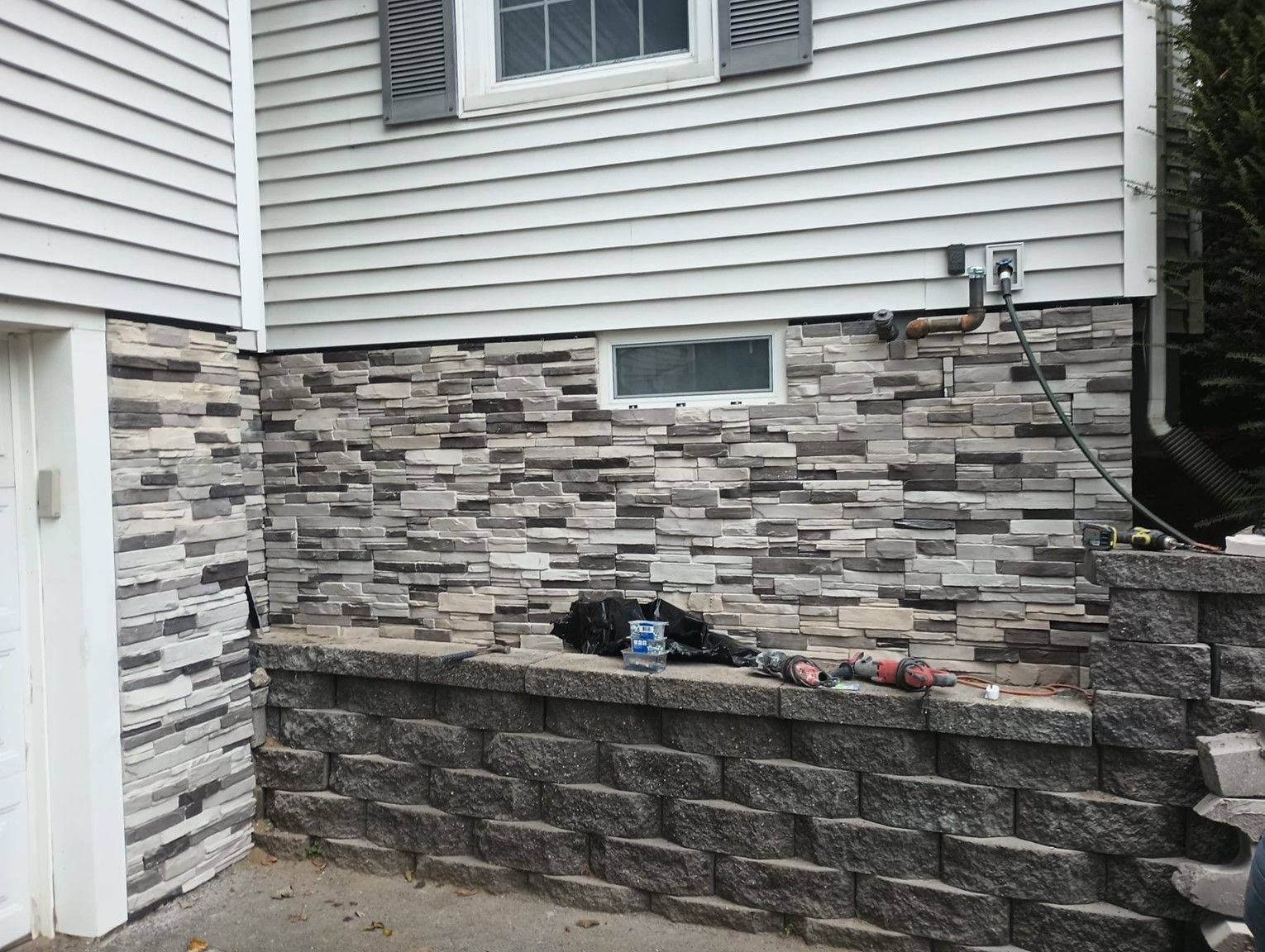A stone wall is being built on the side of a house.