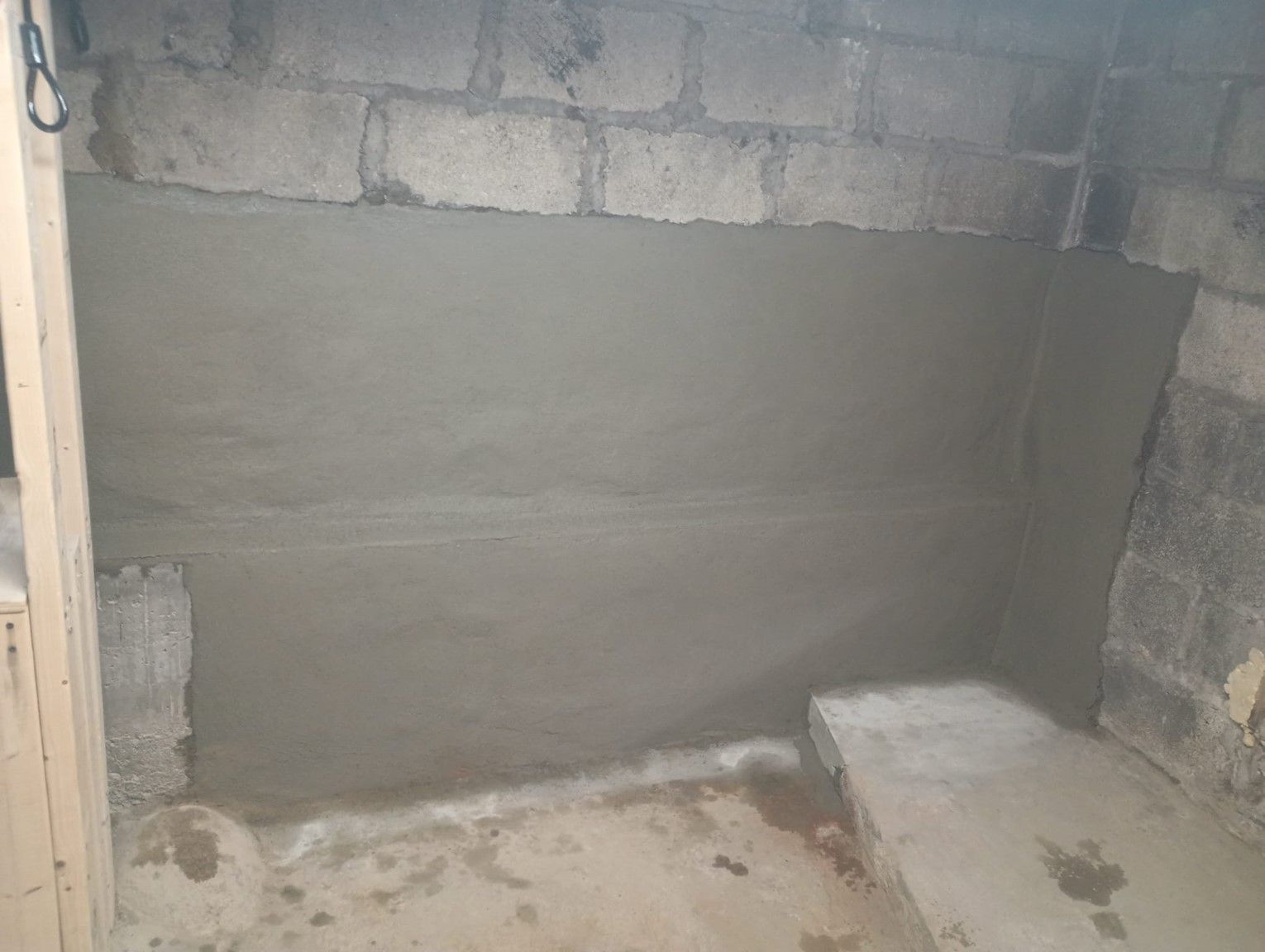 A room with a concrete wall and a bench in it.