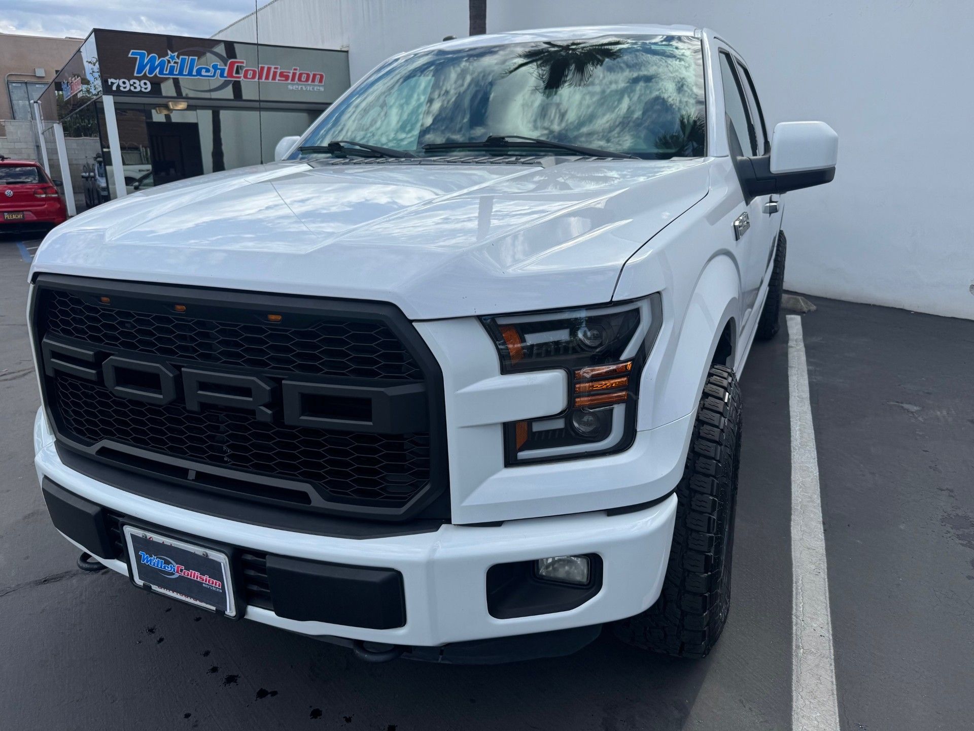 White Ford F-150 truck with a black Raptor-style grille parked in a lot.
