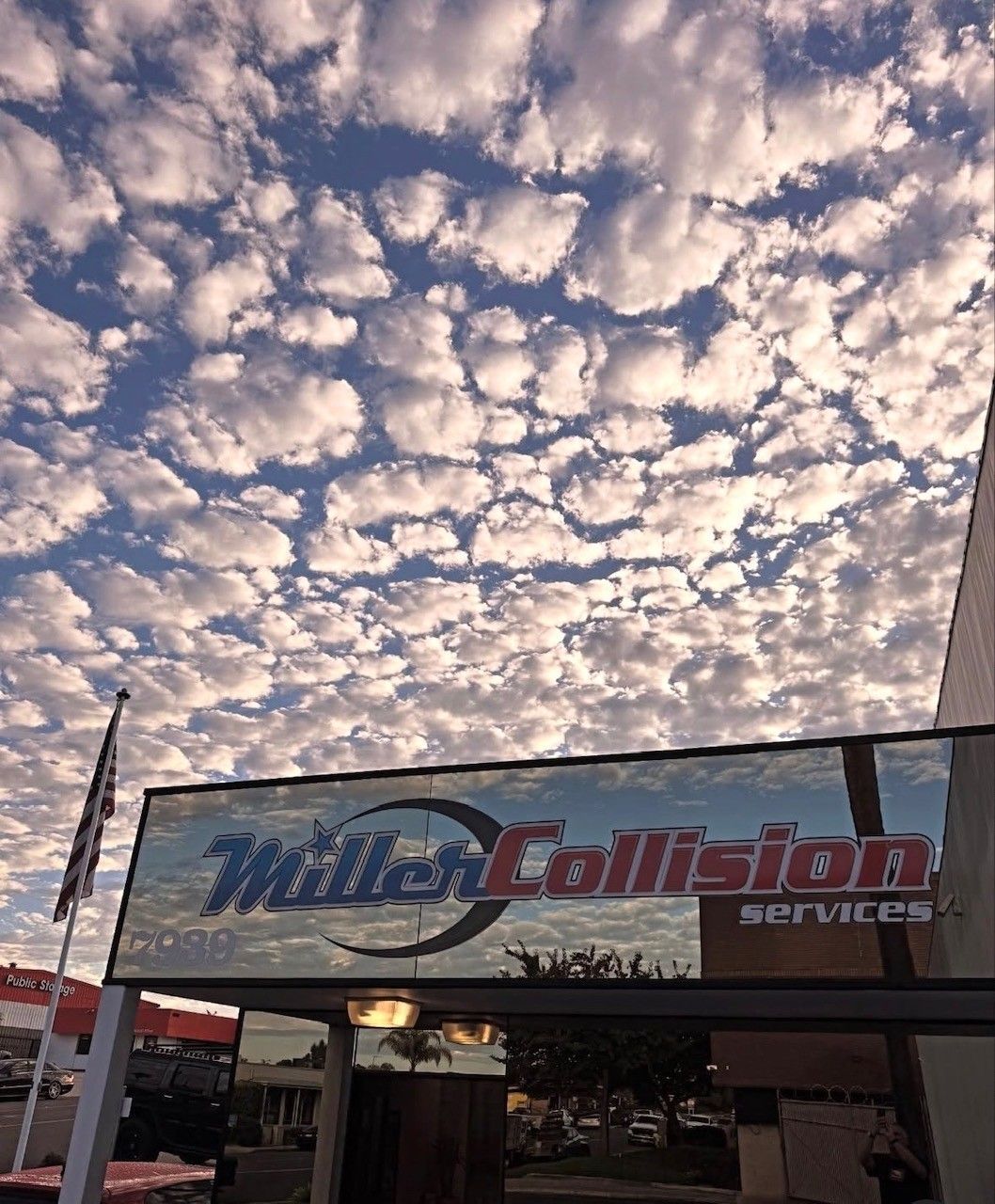 A Miller Collision Services sign under a dramatic, cloudy blue sky.