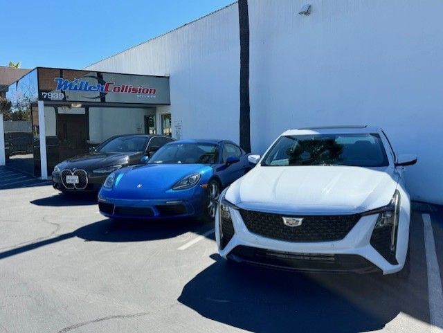 Three luxury cars parked in front of Miller Collision auto repair shop on a sunny day.