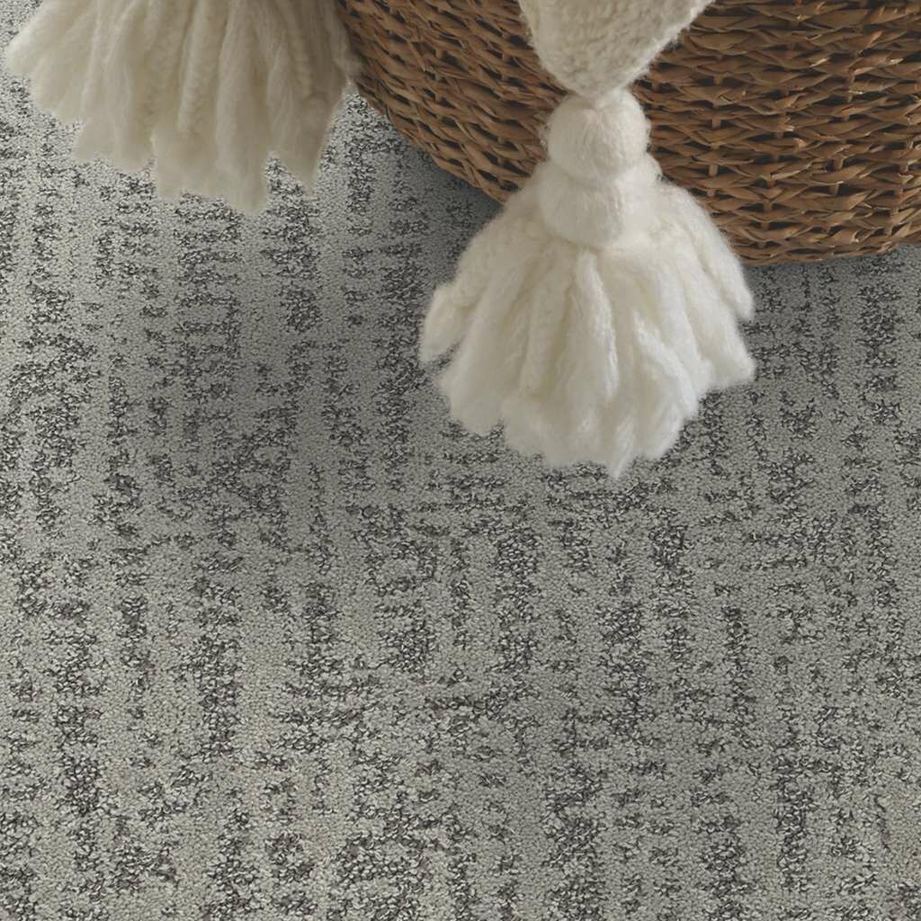 A close up of a carpet with a basket in the background.