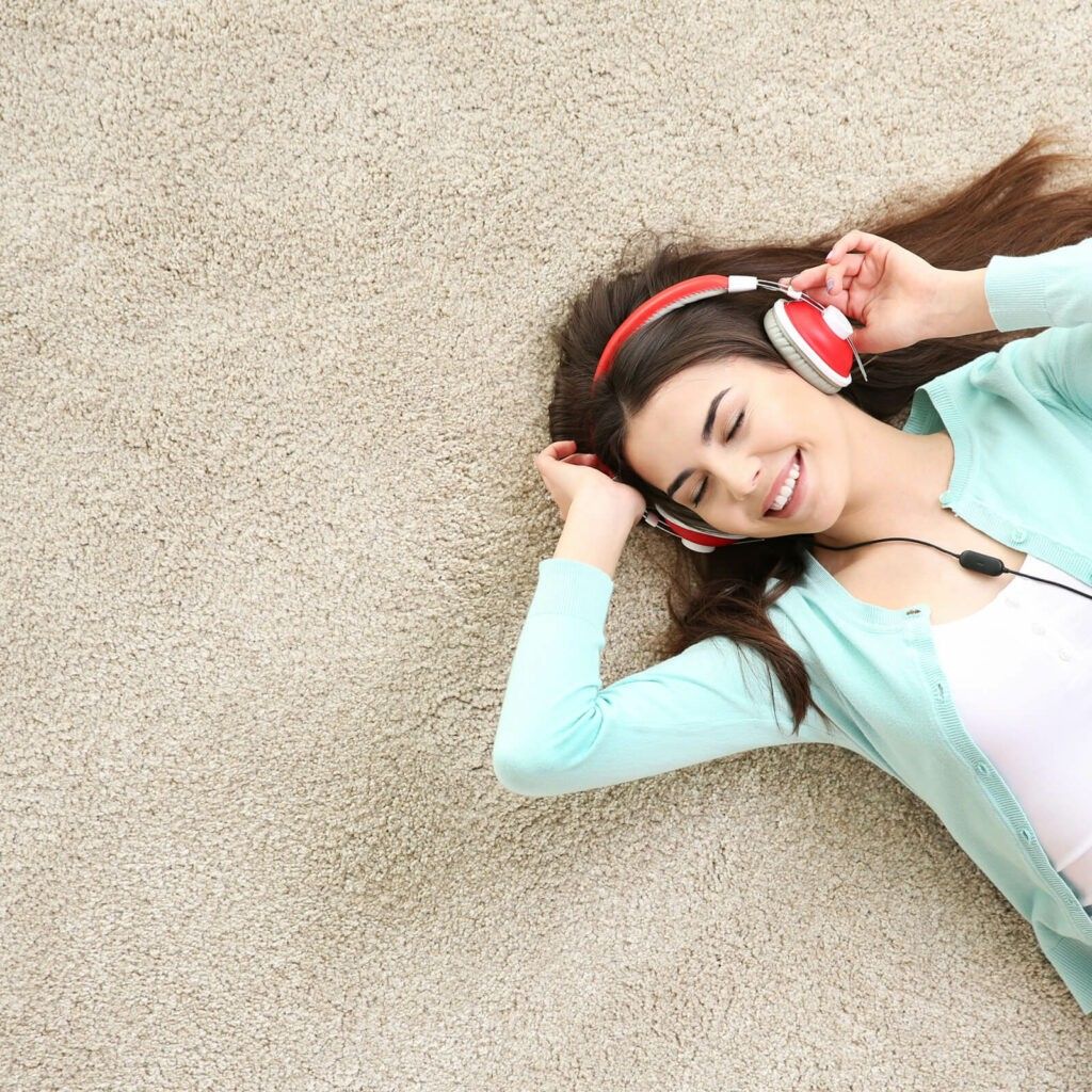 A woman is laying on the floor wearing headphones.