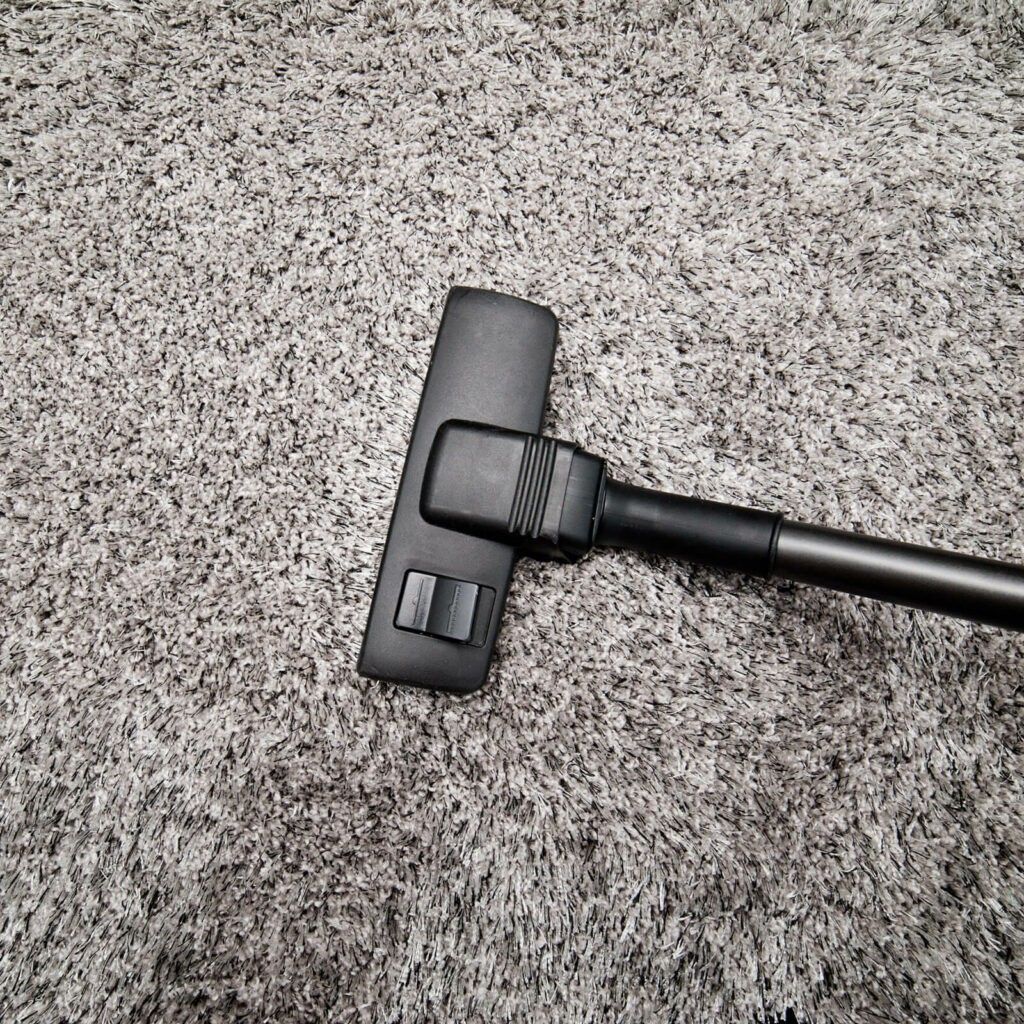 A vacuum cleaner is sitting on top of a carpet.