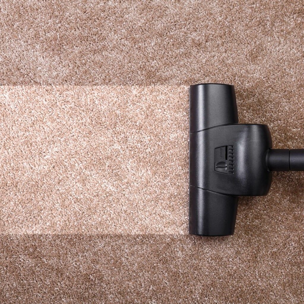 A vacuum cleaner is cleaning a brown carpet.