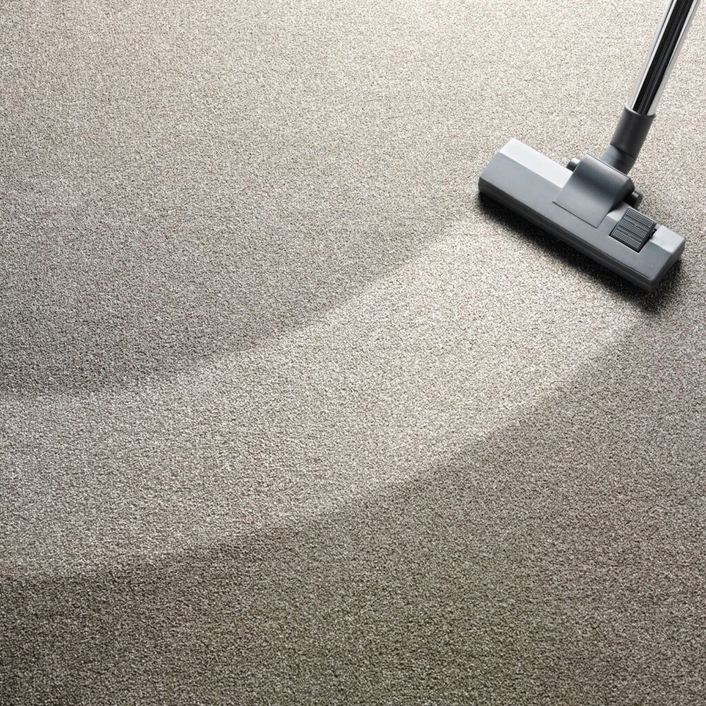 A vacuum cleaner is cleaning a carpet on the floor.