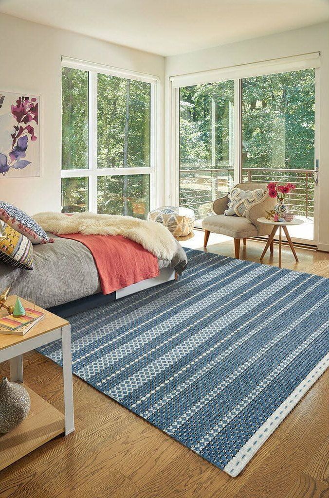 A bedroom with a bed , chair , table and rug.