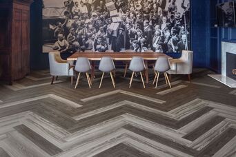 A dining room with a table and chairs and a large picture on the wall.