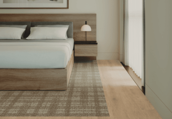 A bedroom with a bed , nightstand , lamp and rug.