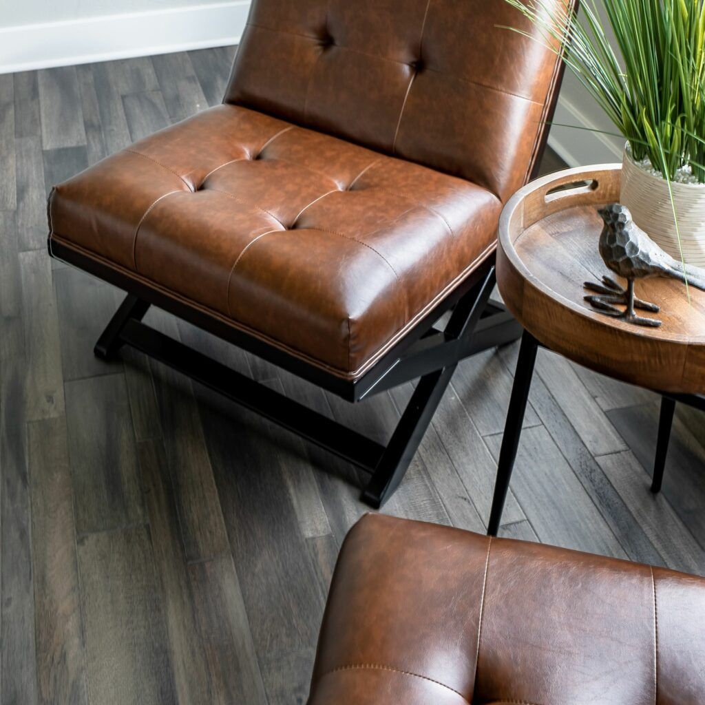 A brown leather chair is sitting next to a wooden table with a bird on it.
