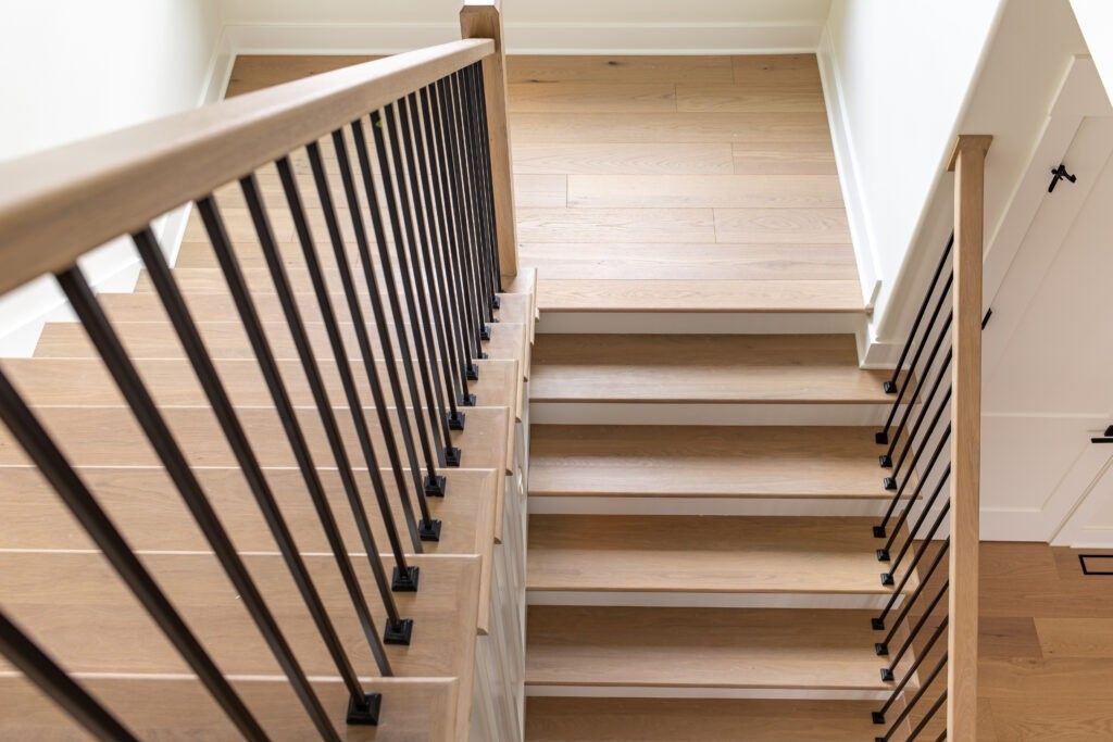 The stairs are made of wood and metal and have a black railing.