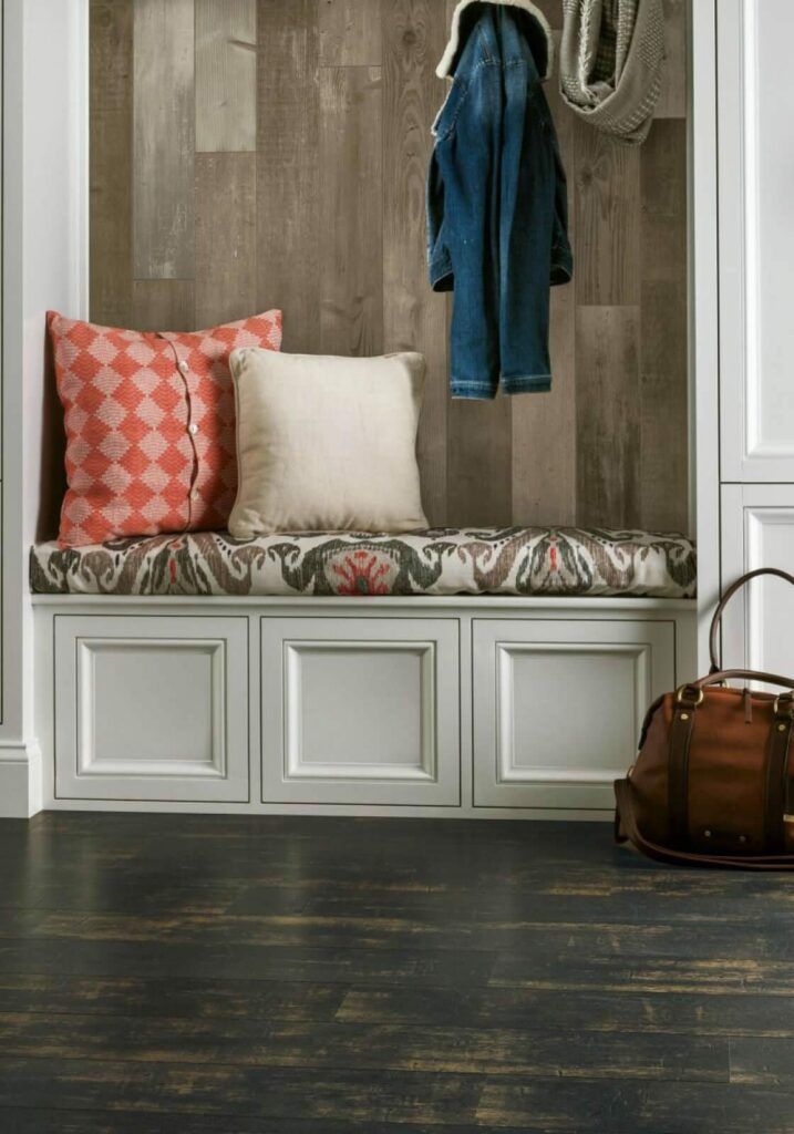 There is a bench with pillows on it in the hallway.