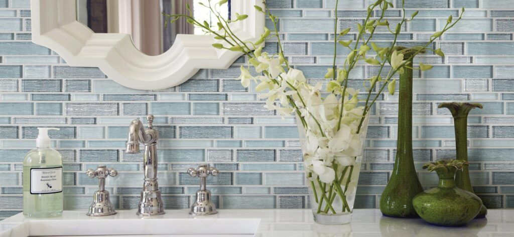 A bathroom with a sink , mirror , vases and flowers.