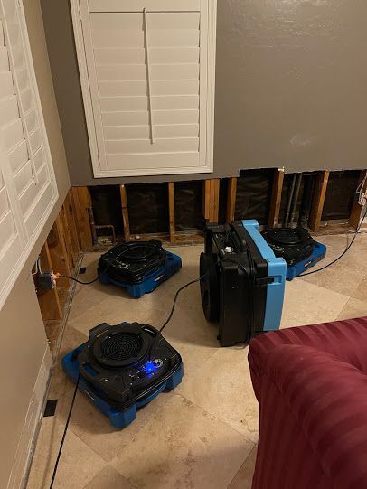 Two robotic vacuums near exposed wall studs in a room under renovation