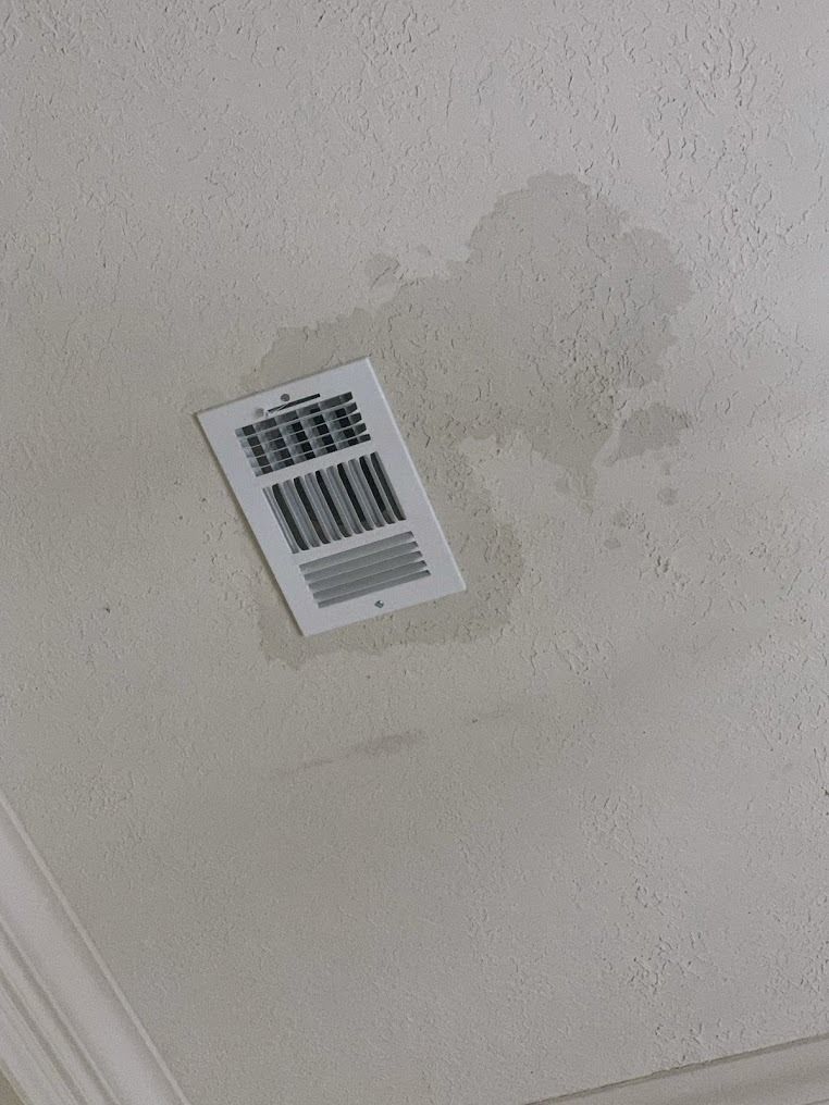 Small barcode label on a light gray wall with a water stain nearby