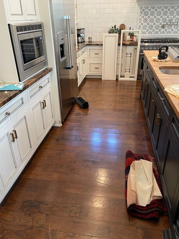 Kitchen with white cabinets, dark wood floor, and a pet bed near the island.