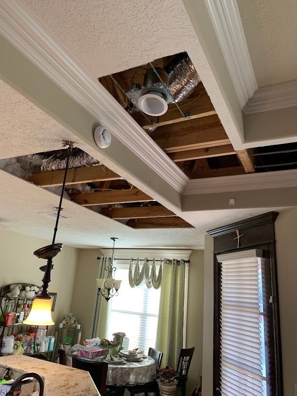 Dining room with a damaged ceiling exposing wood framing and a hanging light fixture