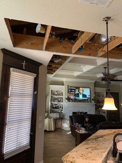 Living room with exposed ceiling beams, TV on, and a kitchen island in the foreground