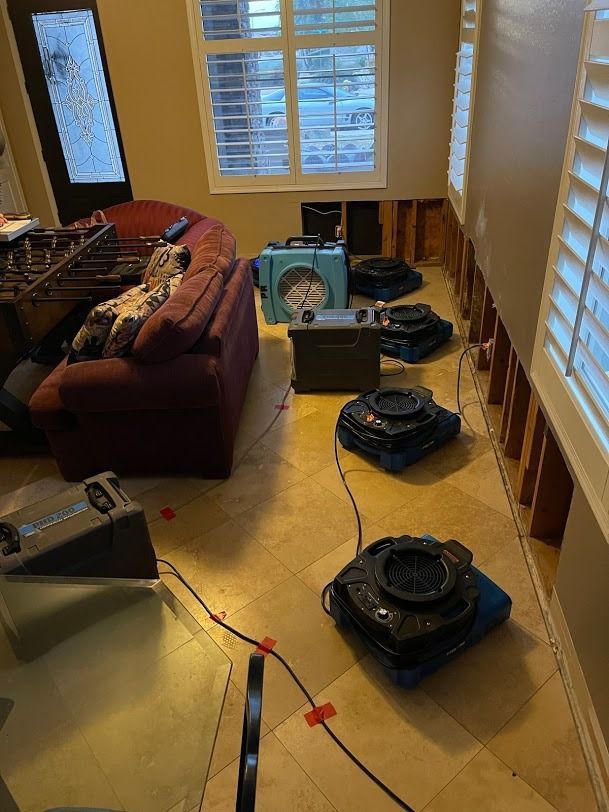 Living room with several floor fans and a portable fan near a couch and windows