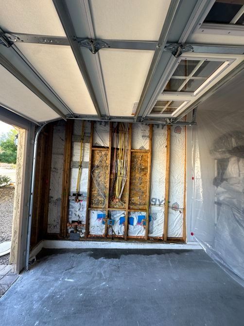 Empty garage interior with exposed wall framing and unfinished drywall on one side