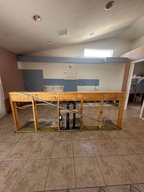 Empty room with tiled floor, damaged wooden table, and blue-and-white wall paneling.