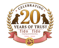 20th anniversary logo for Fido dog daycare and boarding, with gold laurel dogs and pink ribbon