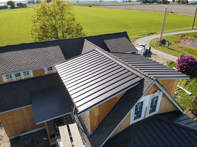 Metal roof on a house under construction, view from above with fields in the background.